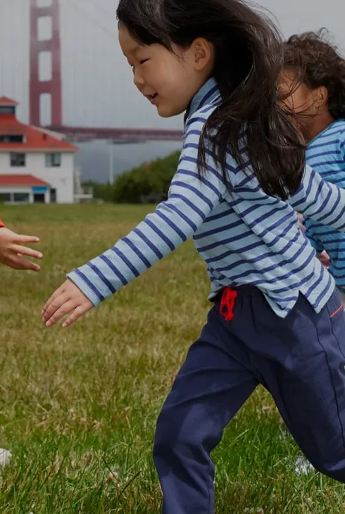 Two children in striped Oso & Me tops playing on grass near the Golden Gate Bridge